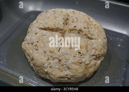 Ungebackener runder Brotlaib, der auf einem Backblech geformt wurde, bevor er in den Ofen gestellt wird. Stockfoto