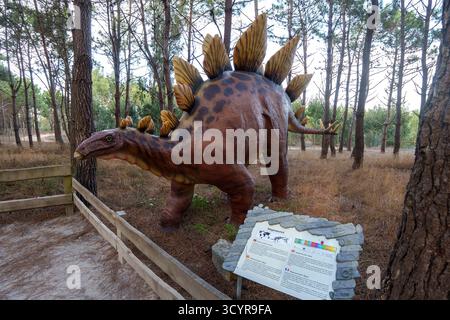 Lebensgroßes Stegosaurus-Modell hinter einem hölzernen Zaun mit einem Infoschild vor dem Dino Parque Dinosaur Themenpark in Lourinhã, Portugal Stockfoto