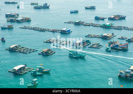 Schwimmende Fischerdörfer, Farmen und farbenfrohe Fischerboote in ruhigem, blauem Wasser vor der Küste der Insel Phu Quoc, Vietnam. Drohnenansicht Stockfoto
