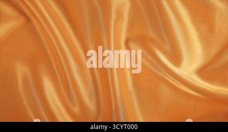 Glattes goldenes Satin-Material mit weichen Falten und glänzender Oberfläche Stockfoto