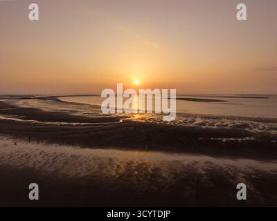 Ein Sonnenuntergang bei Ebbe am Strand von New Brighton, Wirral, England. Die Küstenszene zeigt die Küste, die bei Ebbe und Sonnenuntergang ausgesetzt ist Stockfoto