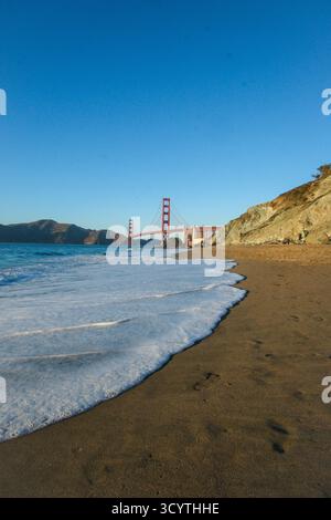 17. OCT 2025 - San Francisco, USA - die Golden Gate Bridge von der westlichen Seite aus gesehen während der Dämmerung vom Marshalls Beach mit Strand und Küste in Th Stockfoto