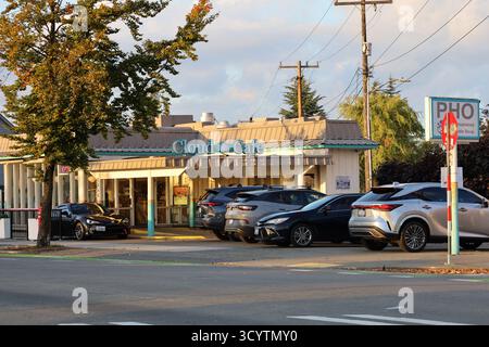 Das Cloud Café in Seattle, Washington, mit geparkten Autos und von Bäumen gesäumter Straße, fotografiert im Abendlicht. Restaurants in der Nachbarschaft und lokale Küche. Stockfoto