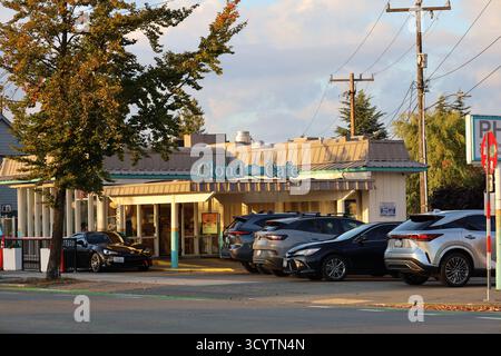 Das Cloud Café in Seattle, Washington, mit geparkten Autos und von Bäumen gesäumter Straße, fotografiert im Abendlicht am 17. Oktober 2025. Stockfoto