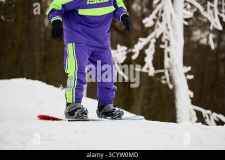 Sportlicher Mann genießt im Winter Snowboarden auf einer verschneiten Piste und zeigt sein Können. Stockfoto