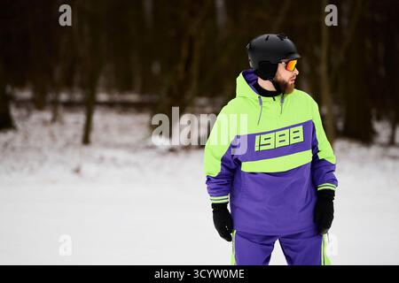 Ein bärtiger Mann genießt das Snowboarden auf einer verschneiten Piste und zeigt sein Können in hellem Winterkleid. Stockfoto