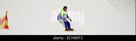 Ein bärtiger Mann genießt Snowboarden auf einer verschneiten Piste und zeigt sein Können im Wintersport, Banner Stockfoto