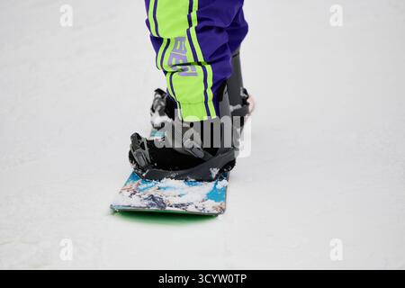 Ein Mann genießt Snowboarden auf einer verschneiten Piste und stellt sein Können im Wintersport unter Beweis. Stockfoto