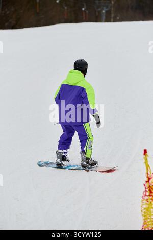 Ein Mann genießt Snowboarden auf einer unberührten schneebedeckten Piste während der Winterkälte. Stockfoto