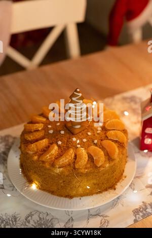 Köstlicher hausgemachter Honigkuchen, dekoriert mit Orangenscheiben und Lebkuchen-Weihnachtsbaum auf Marmortisch. Festliche Feiertagsdesserts und saisonales Backen Stockfoto