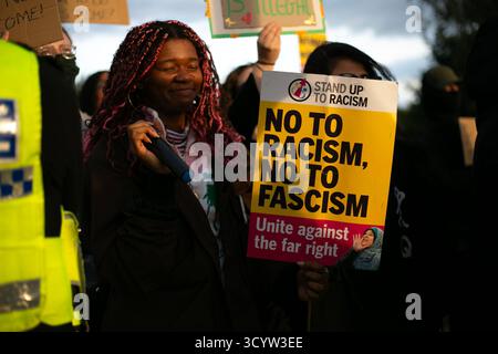 Ein Auftritt für Rassismus-Anhänger, der Plakate "Nein zum Rassismus" und "Nein zum Faschismus" auf einer Gegendemonstration gegen eine Anti-Migranten-Demonstration draußen hält Stockfoto