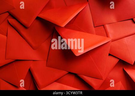 Nahaufnahme roter Umschläge, die ein sich wiederholendes Muster bilden. Nützlich für Konzepte wie Kommunikation, Liebesbriefe, Mailing oder dekorative Hintergründe. Stockfoto