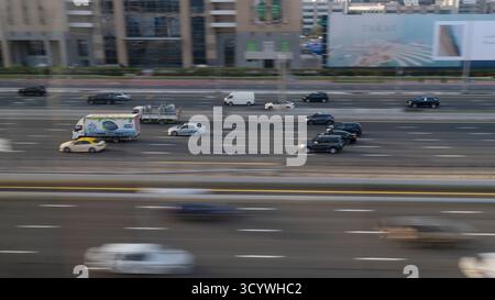 Dubai, Sheikh Zayed Rd, VAE - 3. Februar 2023: Eine Vielzahl von Autos bewegt sich schnell auf einer breiten, mehrspurigen Stadtautobahn. Gebäude und Reklametafeln sind es Stockfoto