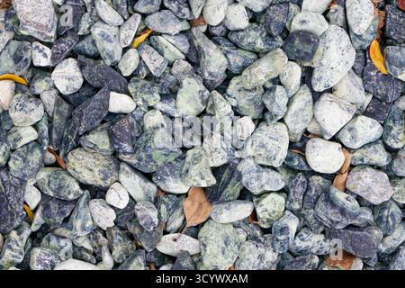 Eine detaillierte Nahaufnahme von dekorativen Steinen und Kieselsteinen in Grün-, weiß- und Blautönen. Das Bild zeigt natürliche Muster und Texturen, ideal für bac Stockfoto