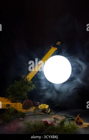 Ein Kran in einer geheimnisvollen Landschaft, der den Mond hochhebt. Stockfoto