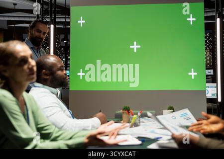 Das multiethnische Projektteam arbeitet spät an der Anzeige von Kopierflächen in einem multinationalen Firmenbüro und überprüft Prognosedaten und Leistungskennzahlen in Berichten. Ziele und Vorschläge für den Erfolg. Stockfoto