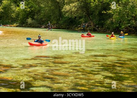 Kajakfahrer paddeln auf dem kristallklaren türkisfarbenen Wasser des Flusses Soča in Slowenien und genießen bei Sommersonne Wassersportarten Stockfoto