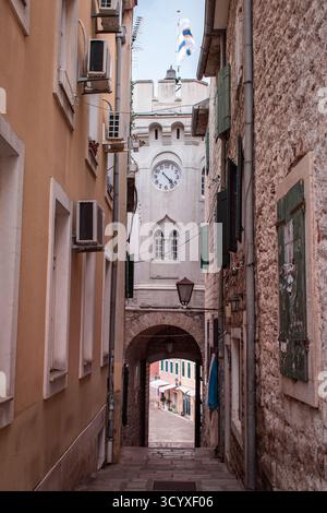 Eine enge Straße in der Altstadt Herceg Novi, Montenegro, gesäumt von alten Backsteinhäusern, die an einer Kirche endet und zum Stadtplatz führt. Stockfoto