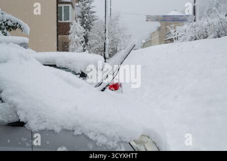 Auto bedeckt mit dickem Schnee nach starkem Schneefall in Wohngebieten. Winterszene mit geparkten Fahrzeugen, die im Schnee vergraben sind und kaltes Wetter und Trans zeigen Stockfoto