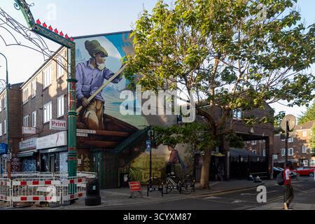 London, UK, 2. Mai 2025. Ein großes, farbenfrohes Streetart-Wandbild, das eine Person zeigt, die ein Boot rudert, bedeckt die Seite eines Gebäudes an einer londoner Straßenecke. Stockfoto