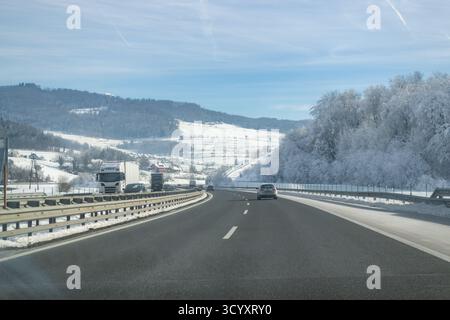 Autos, die auf der Winterautobahn durch verschneite Landschaften in Europa fahren Stockfoto