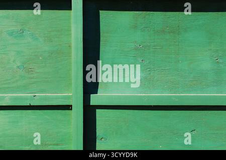 Abgenutzter grüner Holzzaun mit Schatten und Linien Stockfoto