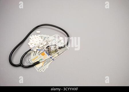 Ein Stethoskop und verschreibungspflichtige Tabletten auf US-100-Scheine. Stockfoto