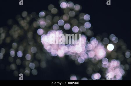 Das Bild ist ein verschwommenes Feuerwerk am Himmel. Das Feuerwerk ist im gesamten Bild verstreut, wobei einige näher am Zentrum und andere weiter entfernt sind Stockfoto