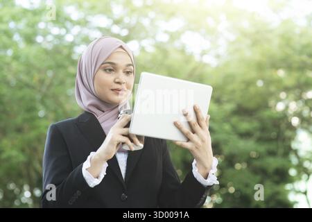 Muslimische Geschäftsfrau trinkt Kaffee, während sie morgens zur Arbeit geht Stockfoto