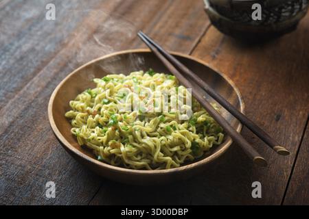 Gekochte japanische Ramen, getrocknete Nudeln mit Essstäbchen auf rustikalem Holztisch, bei schwachem Licht Stockfoto