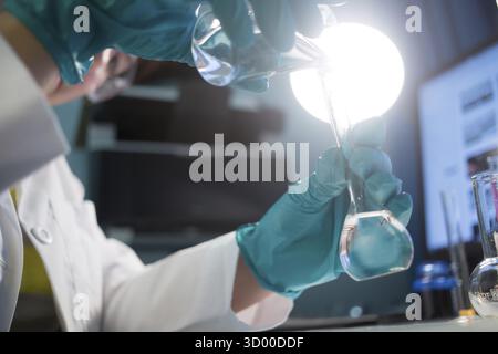 Labortechniker in Gummihandschuhen mit Kolben im Chemielabor Stockfoto