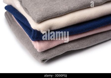 Eine Gruppe warmer Pullover auf weißem Hintergrund. Stapel gefalteter Pullover auf weißem Hintergrund. Stockfoto