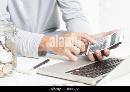 Ein Mann, der seine Buchhaltung macht, mit Laptop-Computer, Taschenrechner, Tagebuch und Geld. Finanzberater arbeitet Stockfoto