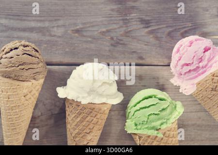 Schokolade, Vanille, Matcha und Erdbeereis im Kegel auf rustikalem Holz Vintage Hintergrund Stockfoto