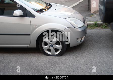Cremona, Italien - 2. Oktober 2025 Ford Fiesta Silber auf Asphalt geparkt mit einem leeren Vorderrad, Panne am Straßenrand, Reifenreparatur oder Notfall erforderlich Stockfoto