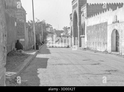 Vormittagsszene in der Todesstadt in Kairo, Ägypten, mit Einwohnern, die an einer ruhigen Straße neben historischen Mausoleen und Grabbauten sitzen. Stockfoto