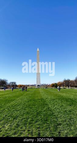 Washington, DC, USA - 22. November 2023: Heller Tag in der National Mall mit dem Washington Monument, das über einem grünen Rasen thront und Besucher. Stockfoto