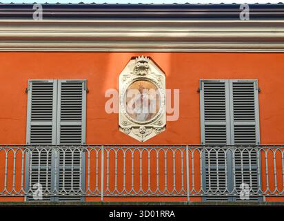 Votivschrein mit einem Fresko von Madonna und Kind in einem reliefförmigen Rahmen, an der Fassade eines alten Gebäudes im historischen Zentrum, Bra (Cuneo), Italien Stockfoto