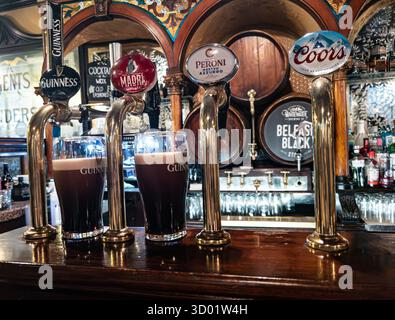 Nahaufnahme von Bierzapfen mit Guinness-, Madri-, Peroni- und Coors-Branding in einer traditionellen Pub-Bar mit gegossenen Pints und Vintage-Einrichtung Stockfoto