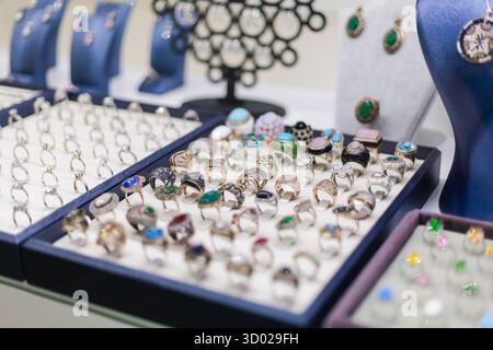Zahlreiche Ringe und Ohrringe sind in einem Juweliergeschäft ausgestellt. Jedes Stück verfügt über einzigartige Designs, farbenfrohe Edelsteine und zarte Details, Stockfoto