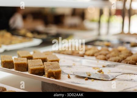 Die Gäste genießen eine Auswahl an Süßigkeiten, darunter Fudge und Kekse, die auf eleganten Tabletts bei einem Dessertbuffet in festlicher Atmosphäre serviert werden und die Freude fesseln Stockfoto