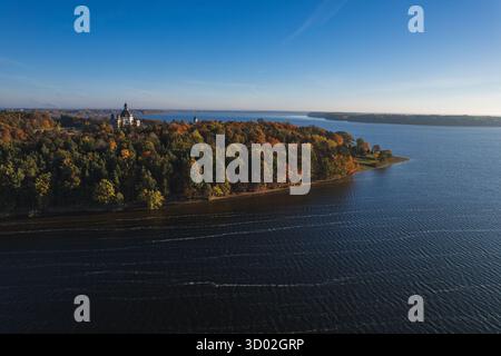 Weite Luftaufnahme des Klosterkomplexes Pazaislis, eingebettet in den Herbstwald neben dem ausgedehnten Kaunas Reservoir unter einem klaren blauen Himmel. Hoher ph-Wert Stockfoto