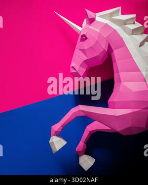 Geometrischer rosafarbener blauer Einhorn-Skulptur doppelter Hintergrund. Die auffällige und moderne geometrische Einhornskulptur in rosa weiß steht auf der Rückseite in rosa Violett Stockfoto