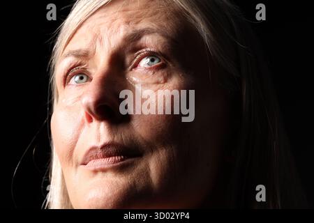 Ältere Frau weint auf schwarzem Hintergrund, Nahaufnahme Stockfoto