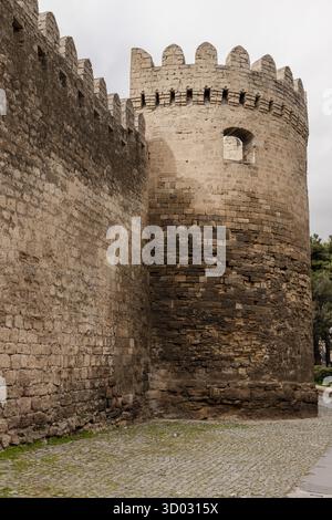 Alte Steinfestungsmauern mit rundem Turm unter hellem Himmel mit hellen Wolken, beispielhaft für historische Architektur und mittelalterliche Verteidigung Stockfoto