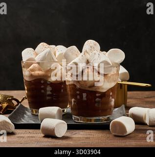 Zwei Gläser heiße Schokolade mit flauschigen Marshmallows auf einem Schieferbrett. Eine Nahaufnahme des Wintergetränks. Stockfoto