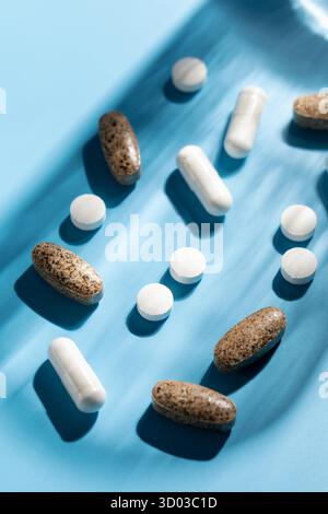 Verschiedene Vitamine, Tabletten und Nahrungsergänzungsmittel auf blauem Hintergrund. Der Begriff der Medizin. Stockfoto