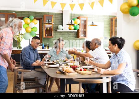 Seniorenfreunde genießen lebhafte Gespräche und gemeinsames Essen zu Hause. Freundschaft, Treffen, ältere Menschen, Sozialisierung || Model veröffentlicht Stockfoto