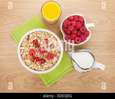 Gesunde Frühstück mit Müsli, Beeren, Milch und Orangensaft auf Holztisch Stockfoto