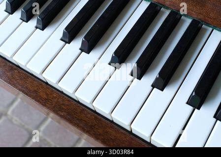 Nahaufnahme von Klaviertasten, ein Musikinstrument mit schwarzen und weißen Tasten. Die hölzerne Klavieroberfläche verleiht einen Hauch von Eleganz. Stockfoto